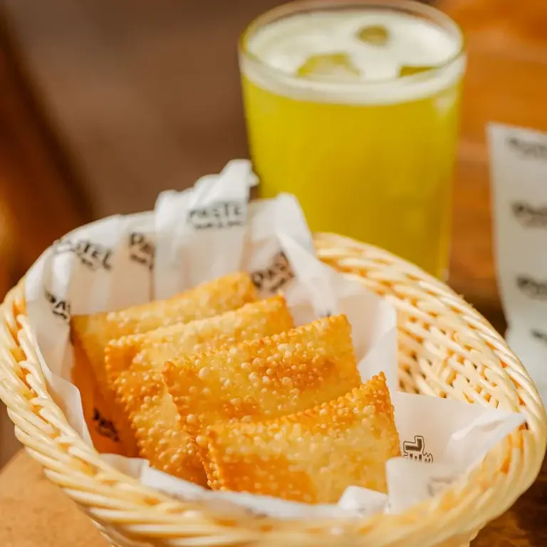 Fotografia mostrando os famosos e requisitados mini pastéis do Pastel Mix. E um caldo de cana ao fundo para acompanhar.