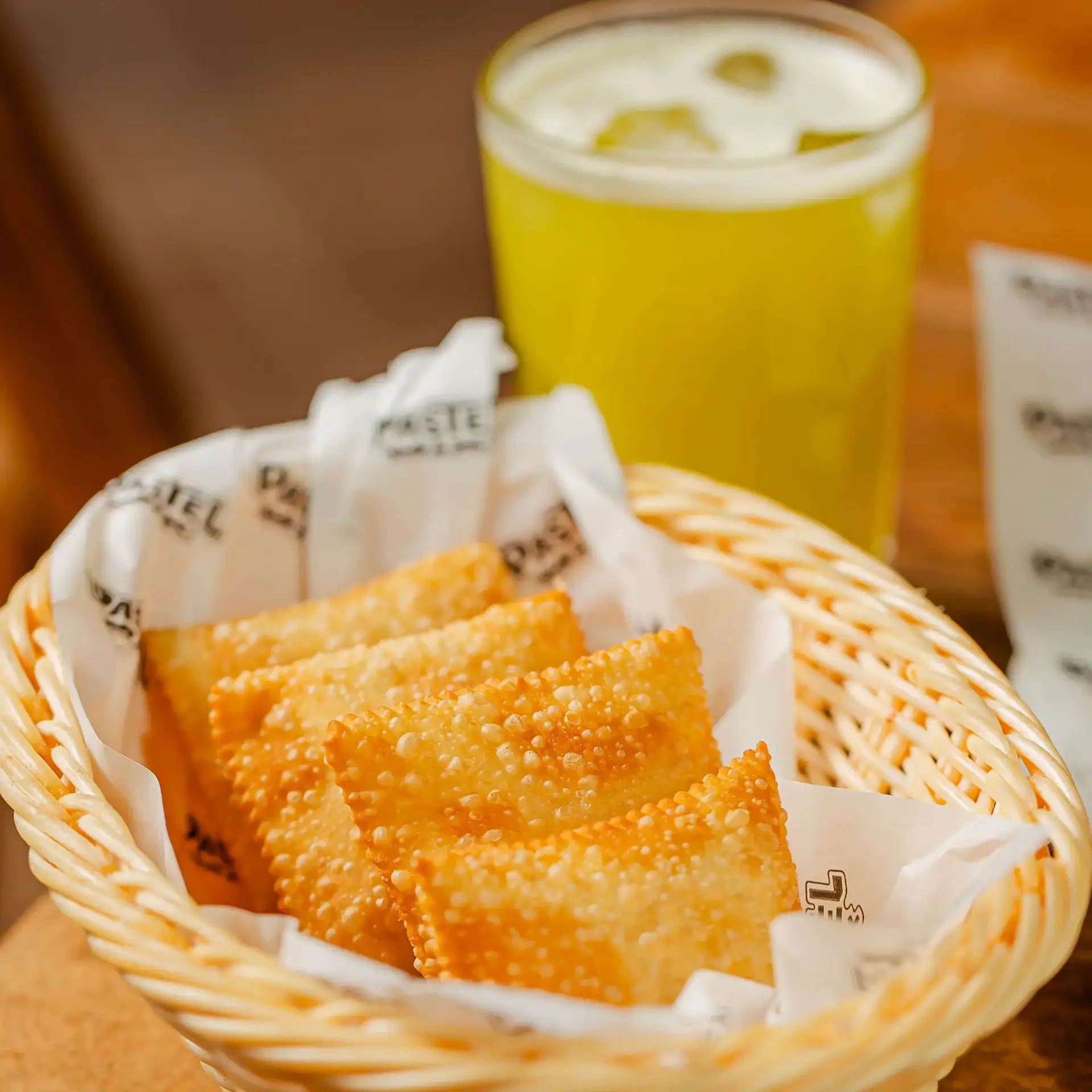 Fotografia mostrando os famosos e requisitados mini pastéis do Pastel Mix. E um caldo de cana ao fundo para acompanhar.